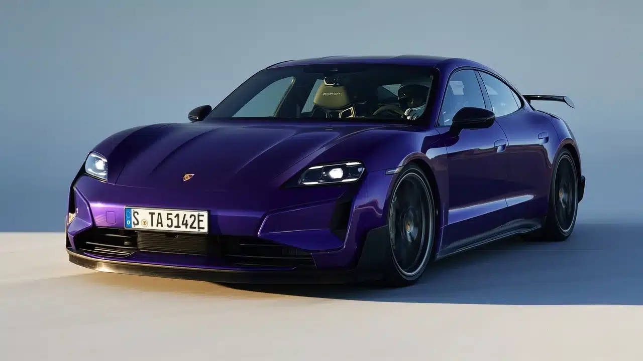 Purple Porsche Taycan Turbo GT Weissach electric car driving on a bright open road with headlights on.